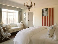 an american flag is hanging on the wall in this bedroom with white bedding and pillows