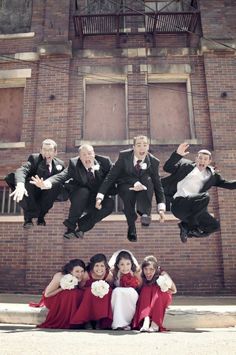 a group of people in suits and ties are jumping into the air with their hands up