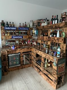 a kitchen with lots of wooden pallets on the wall and shelves filled with bottles