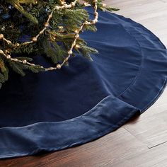 a christmas tree skirt sitting on top of a wooden floor next to a fir tree