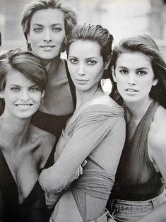 three women are posing for the camera with their arms around each other and one woman has her hand on her shoulder