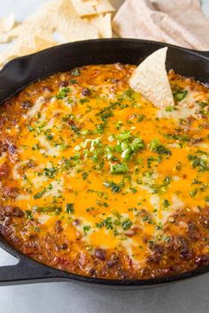 a black skillet filled with cheese and tortilla chips on top of a table