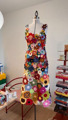 a dress made out of crochet is on display in a room full of books