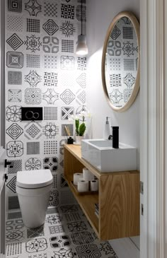 a white toilet sitting next to a wooden cabinet in a bathroom under a round mirror