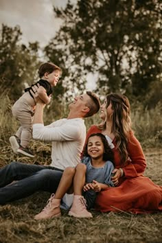 a family sitting on the ground laughing and playing with each other in an open field