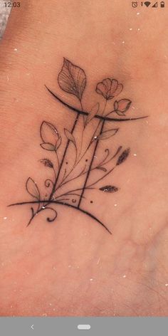 a small flower tattoo on the side of a woman's foot, with leaves and swirls