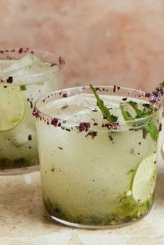 two glasses filled with drinks sitting on top of a counter next to each other and the words smoky serrano - mint margarita recipe