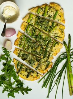 asparagus and other vegetables are laid out on a white surface next to an artisan pizza