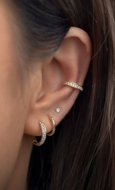 a woman wearing three different types of ear piercings on her left ear and the other half