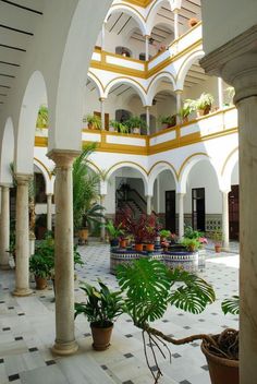 an indoor courtyard with potted plants in the foreground and arches on either side