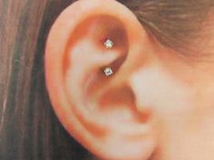 a woman's ear is shown with three diamond studs