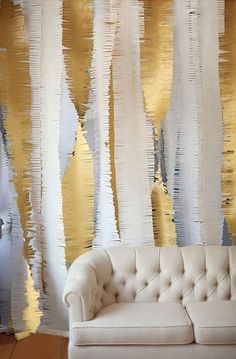 a couch sitting next to a wall covered in gold and white paper streamers on top of it