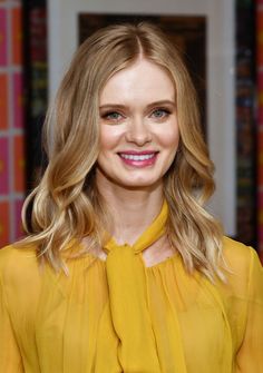 a woman with blonde hair wearing a yellow blouse