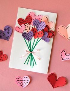 valentine's day card with paper hearts and flowers on pink background surrounded by cut out hearts