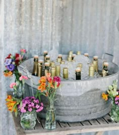 a metal bucket filled with lots of bottles and flowers