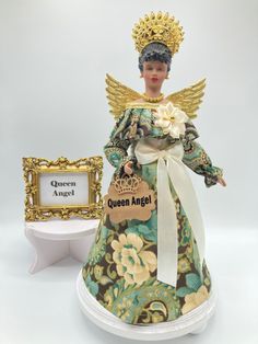 an angel figurine is displayed next to a small plaque that says queen angel