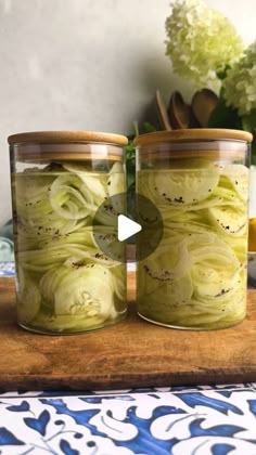 two jars filled with pickles sitting on top of a table