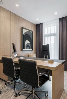 an office with two black chairs and a wooden desk