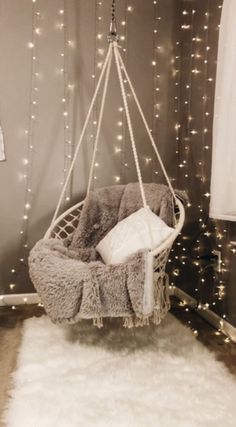 a hanging chair in the corner of a room with christmas lights on the wall behind it