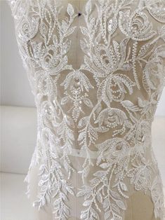 the back of a wedding dress with white lace and flowers on it's skirt