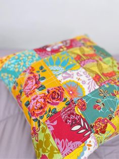 a multicolored patchwork pillow on top of a bed