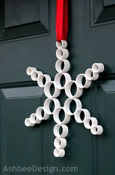 a paper snowflake hanging on a door with a red ribbon attached to it