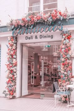 the entrance to an italian restaurant decorated with colorful flowers and greenery, in front of a cafe