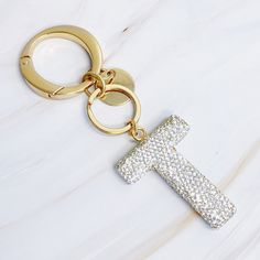 a gold keychain with a cross on it sitting on a white marble surface