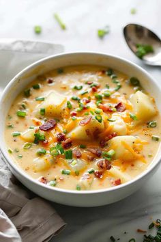 a white bowl filled with potato soup on top of a table next to a spoon