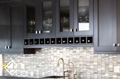 a kitchen with black cabinets and white tile backsplash