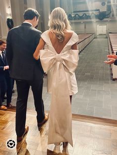 the back of a woman's dress as she walks in front of two men