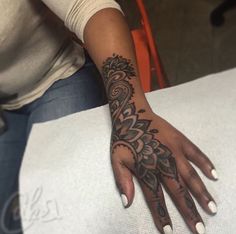 a woman's hand with henna tattoos on her left arm and the middle finger