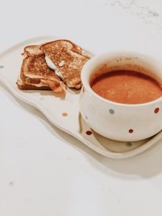 a cup of soup and some toast on a plate