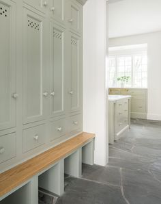 an empty kitchen with white cabinets and wood bench