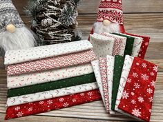 several different types of christmas fabric on a wooden surface with santa hats and snowflakes