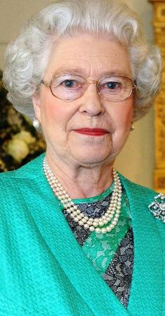 an older woman in a green jacket and pearls