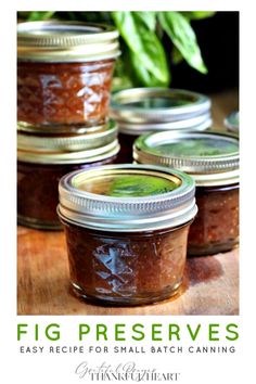 four jars filled with jam sitting on top of a wooden table