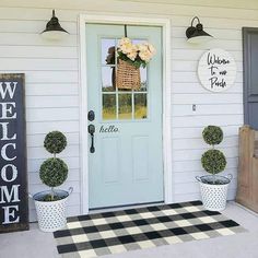 the front door is decorated with potted plants and welcome signs for guests to enter