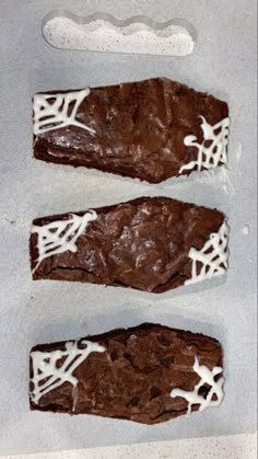 three pieces of brownie with white icing on them sitting on top of a counter