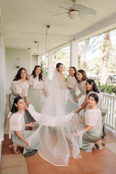 a group of women standing on top of a porch next to each other wearing white dresses