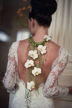 the back of a woman's wedding dress with flowers on her neck and shoulders