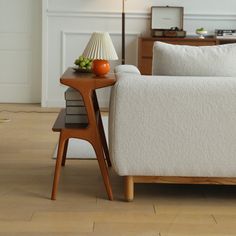 a white couch sitting on top of a wooden floor next to a table with an orange