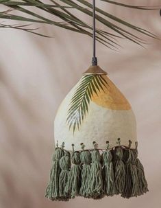 an ornament hanging from a palm tree branch with tassels on it