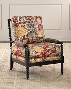 a chair with an ornate pattern on it in front of a white paneled wall