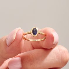 The 14k Solid Gold Oval Blue Ring showcases a captivating bluish-purple iolite gemstone, perfect for an engagement or special celebration. This bezel-set birthstone solitaire ring is a beautiful, handmade piece of jewelry designed for women. Crafted in 14k solid gold, it adds a touch of elegance and uniqueness to her collection. Ring Details   ❥ Gold KT: 14k Solid Gold (also in 10, 18K)  ❥ Gold Color Options: White, Yellow, Rose Gold  ❥ Top Width: 8.00x6.20 mm  ❥ Top Thickness: 4.65 mm  ❥ Band W 14k Gold Sapphire Ring Oval Cabochon, Minimalist Oval Sapphire Ring, Modern Oval Cabochon Sapphire Ring, Modern Sapphire Ring With Oval Cabochon, Minimalist Oval Sapphire Birthstone Ring, Minimalist Sapphire Oval Birthstone Ring, Oval Cabochon Sapphire Promise Ring, Modern Cabochon Sapphire Ring For Gift, Dainty Oval Sapphire Ring Gift