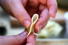 two hands holding small pieces of food in front of a person's hand on a table