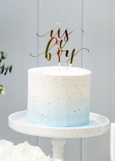 a white cake with blue and gold frosting that says it's boy on top