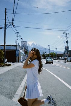 a woman walking across a street while talking on a cell phone