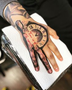 a person with a tattoo on their hand and clock tattooed on the other hand, holding onto a napkin