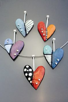 six heart shaped magnets hanging on a clothes line with pins in the shape of hearts